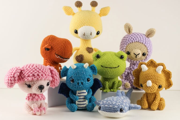 A group of crocheted amigurumi animals sit together. The animals are a poodle, t-rex, dragon, giraffe, frog, whale shark, llama, and triceratops.
