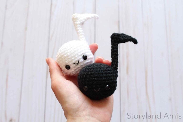 A hand holds two crocheted music notes.