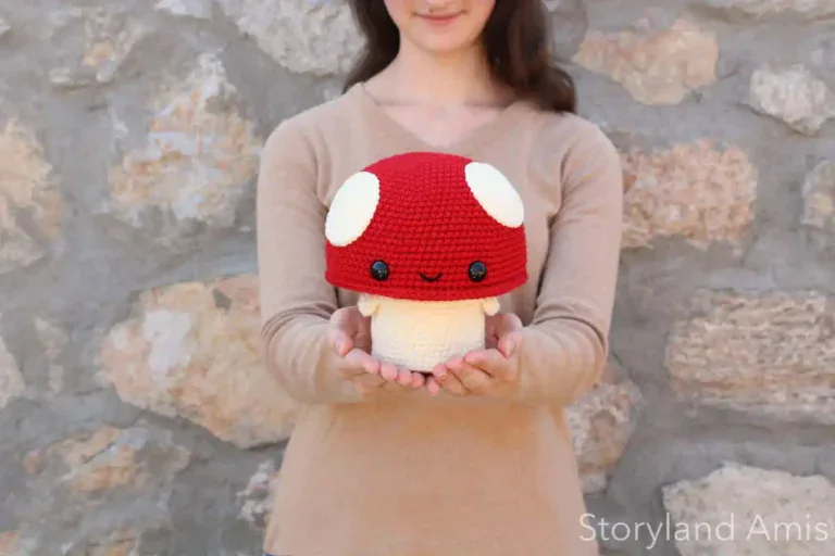 A girl holds up an amigurumi mushroom.