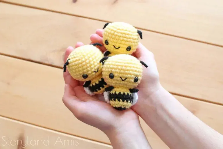 Hands hold up three amigurumi bees.