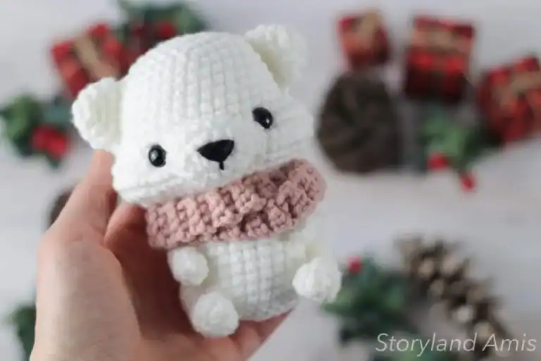 A hand holds up an amigurumi polar bear