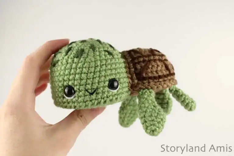 A hand holds up an amigurumi sea turtle.