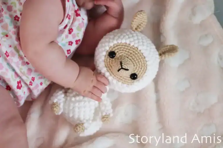 A baby holds an amigurumi llama.