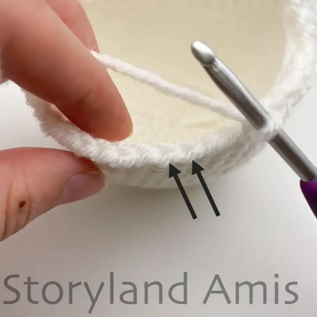 Arrows point to the front loops on a partially finished crochet ghost.