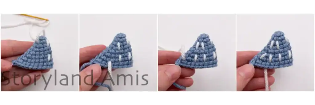 A hand demonstrates how to embroider white stripes on an amigurumi whale shark's fins.