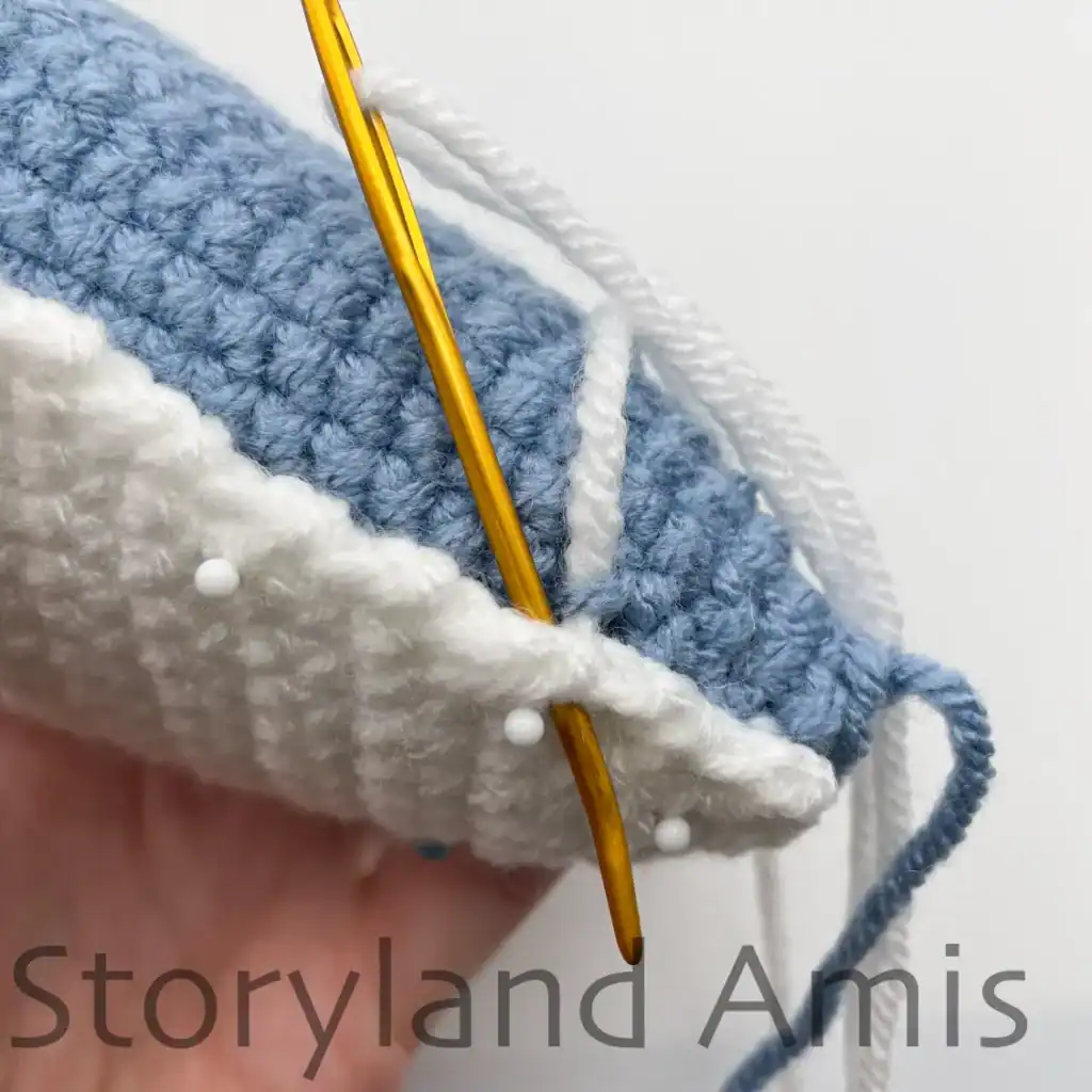 A hand demonstrates how to sew the belly piece to an amigurumi whale shark.