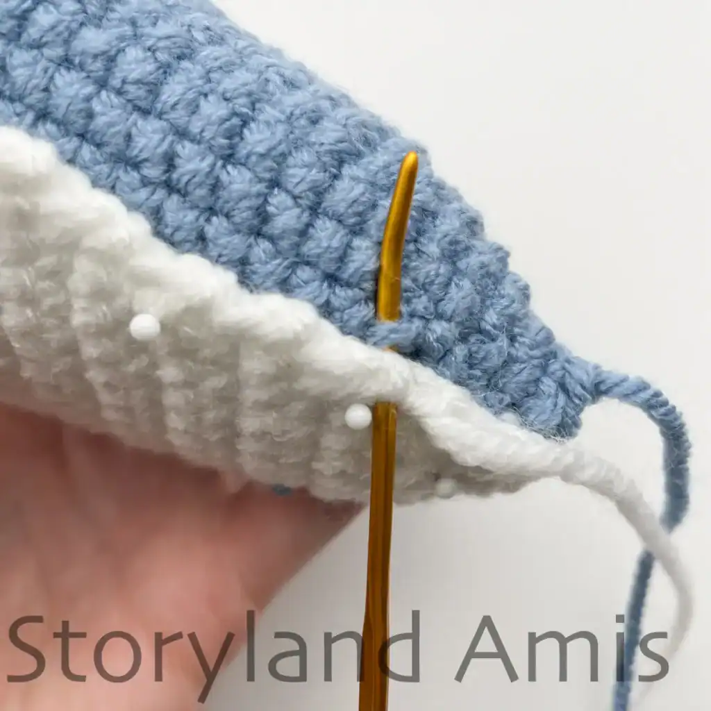 A hand demonstrates how to sew the belly piece to an amigurumi whale shark.