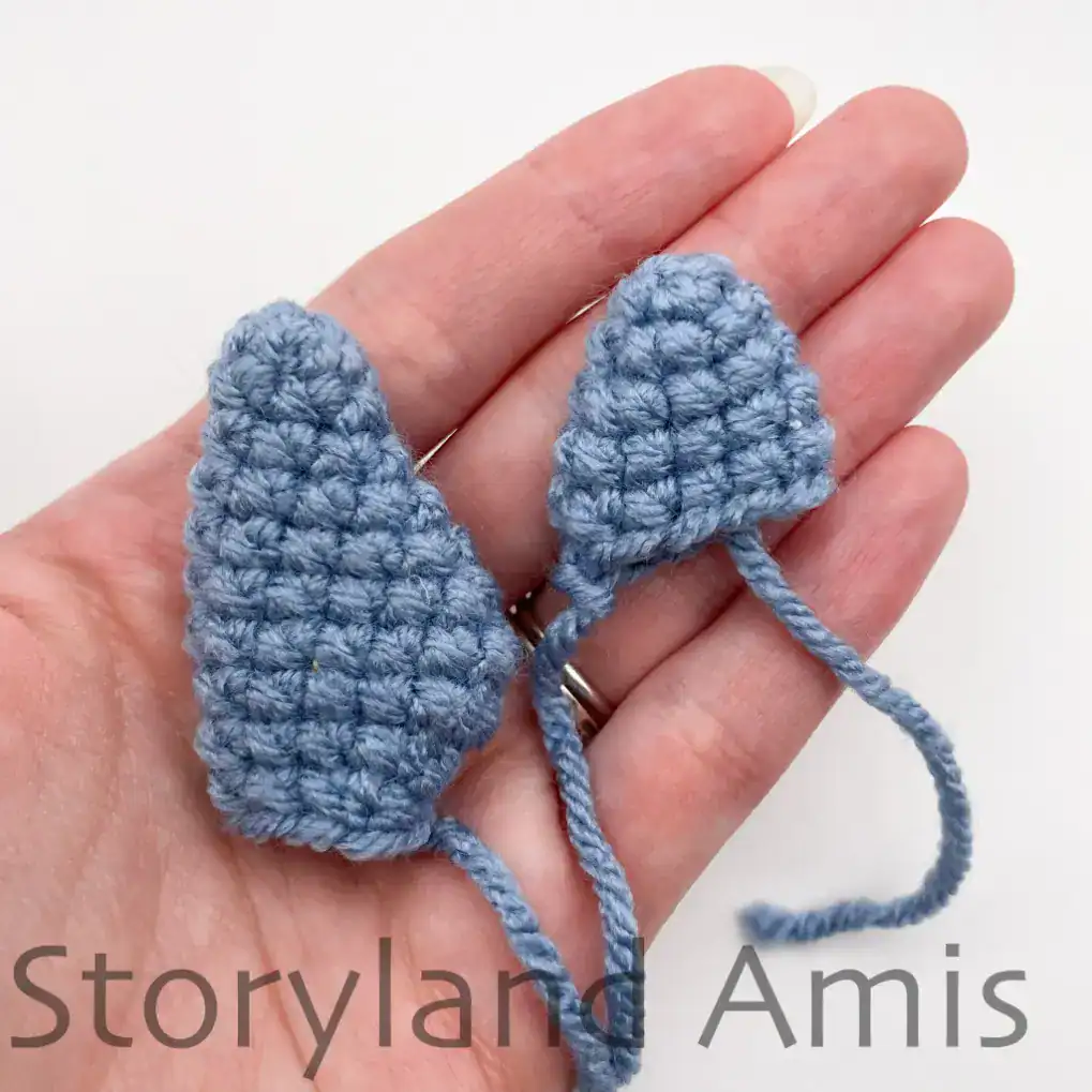 A hand holds two crocheted whale fins for an amigurumi whale shark.