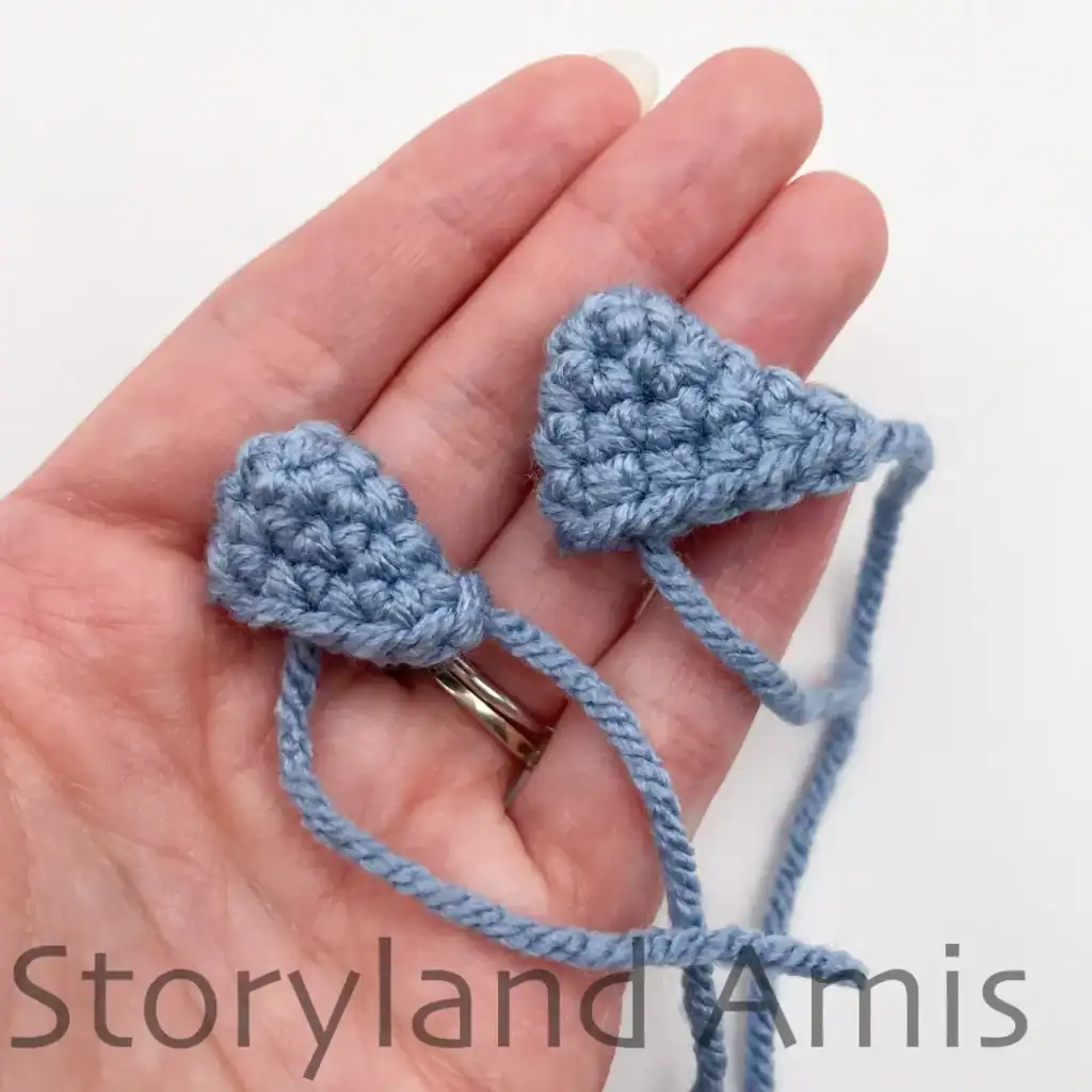 A hand holds up two crocheted whale shark fins.