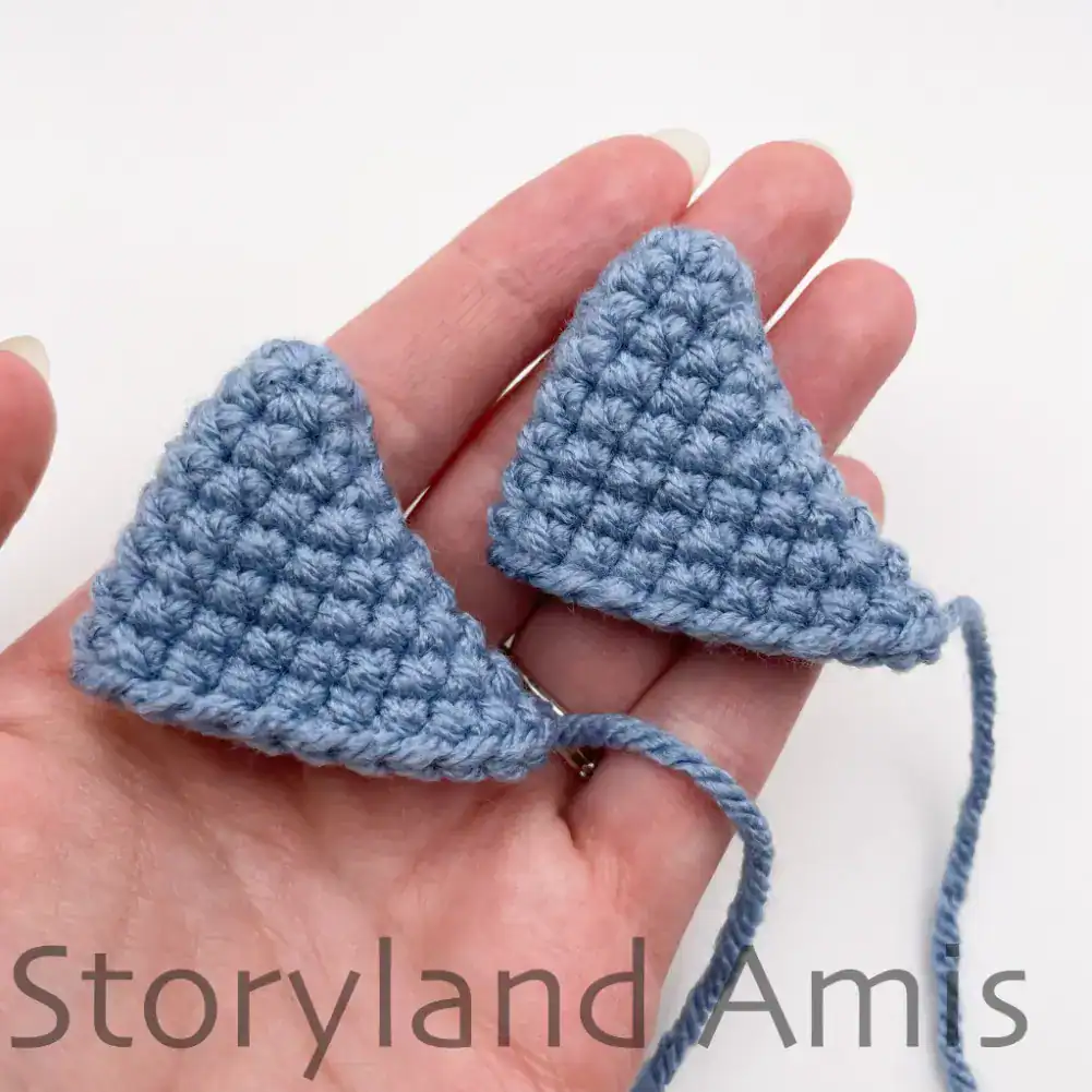 A hand holds up two crocheted whale shark fins.