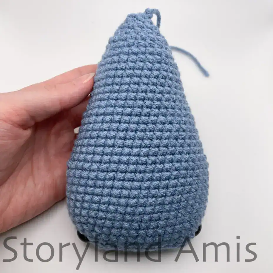 A hand holds a partially finished amigurumi whale shark.
