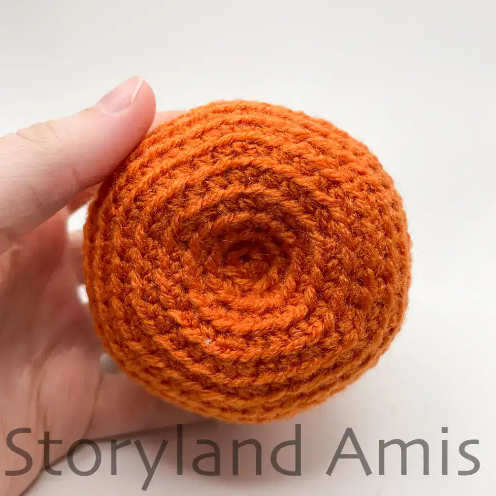A close-up of the bottom of a crocheted pumpkin.