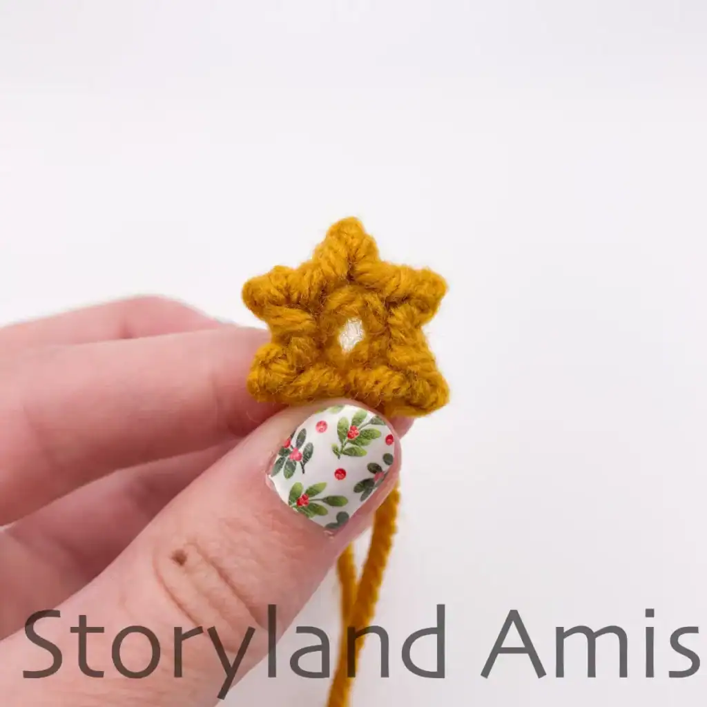 A hand holds a mini crocheted star.