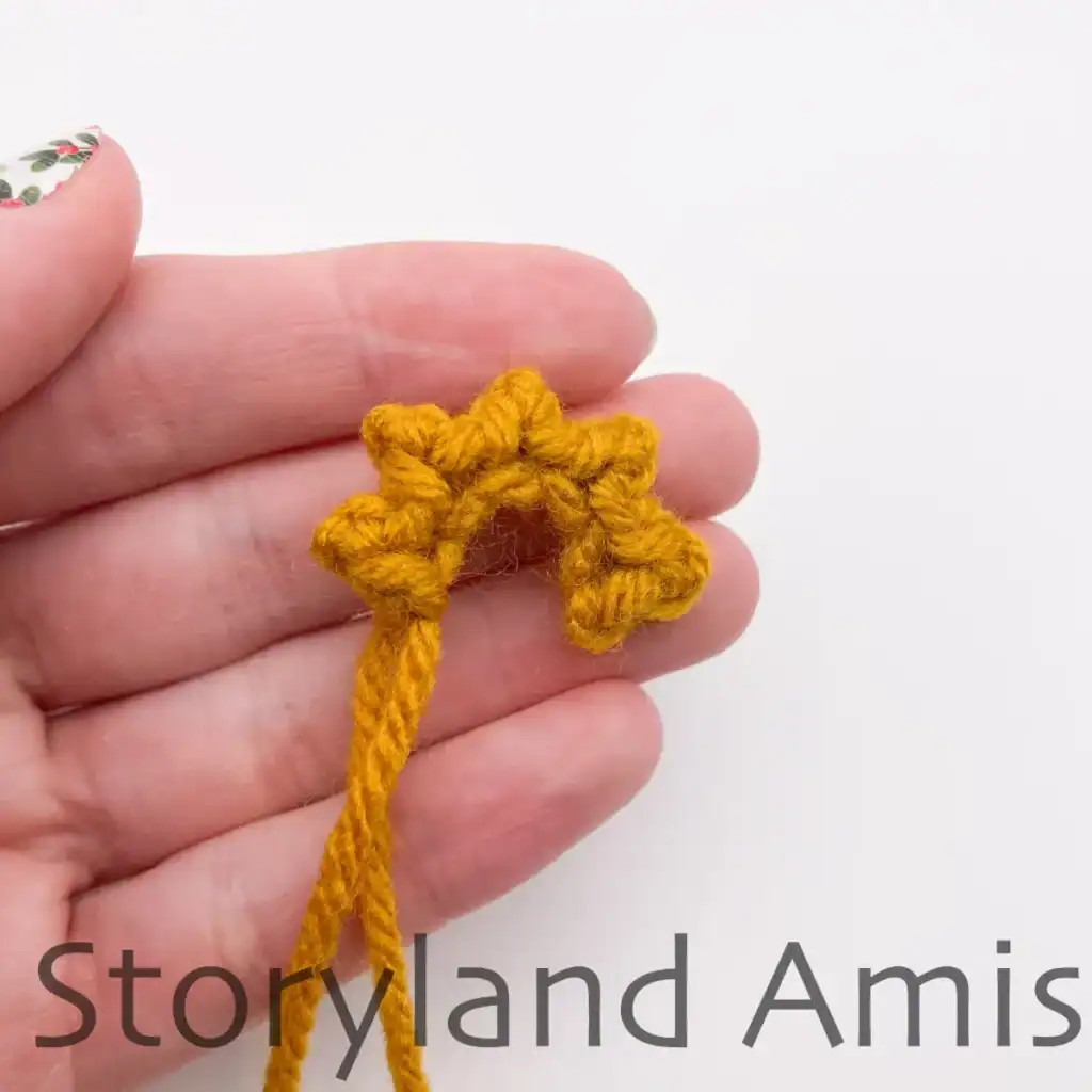 A hand holds a crocheted star before the two ends are joined together and the shape is created.