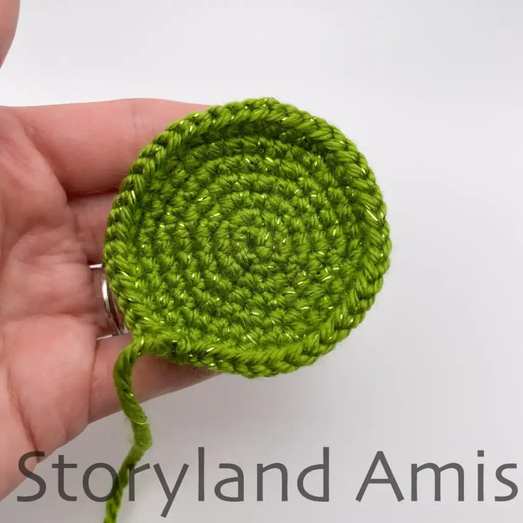 A hand holds the crocheted bottom piece for an amigurumi Christmas tree.