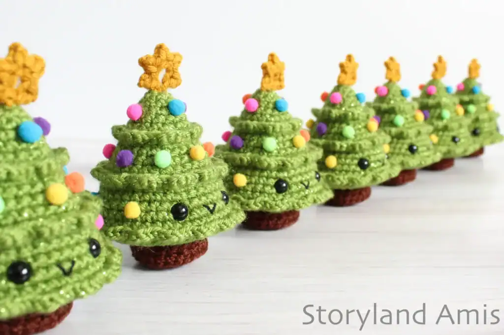 Seven mini amigurumi Christmas trees are lined up in a row.