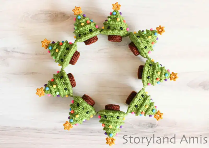 Nine mini Christmas trees form a circle on a wooden table.