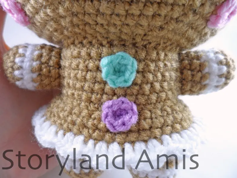A close-up of the front of the body of an amigurumi gingerbread girl.