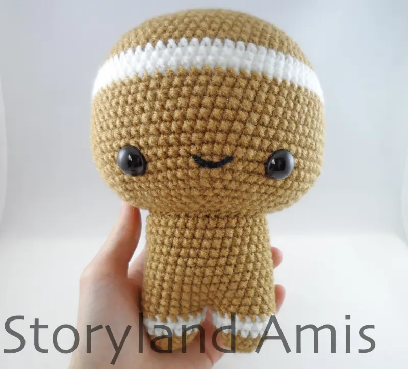 A hand holds a partially finished amigurumi gingerbread boy.