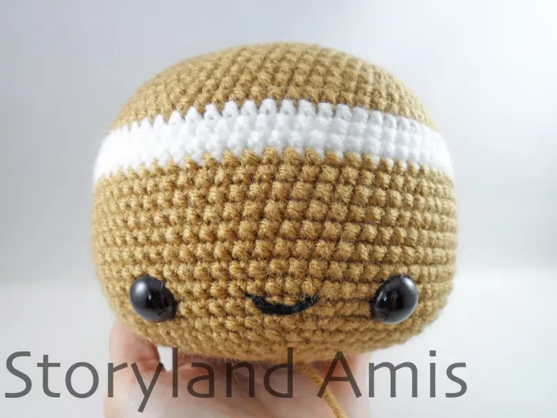 A hand holds a crocheted gingerbread man head.