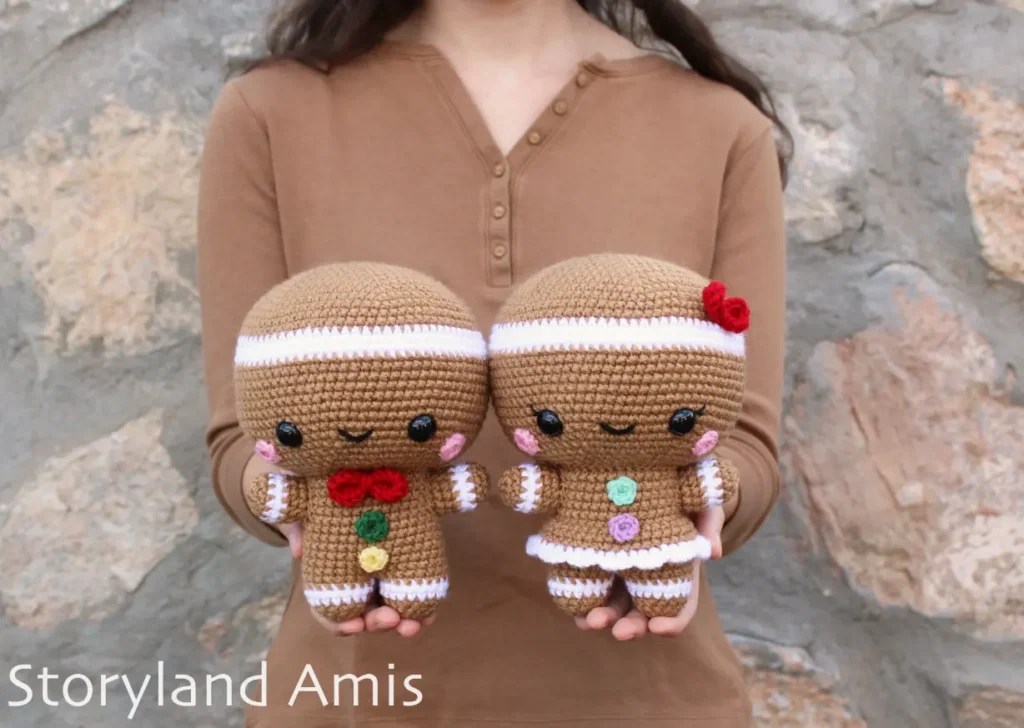 A girl holds a crocheted gingerbread man and girl.