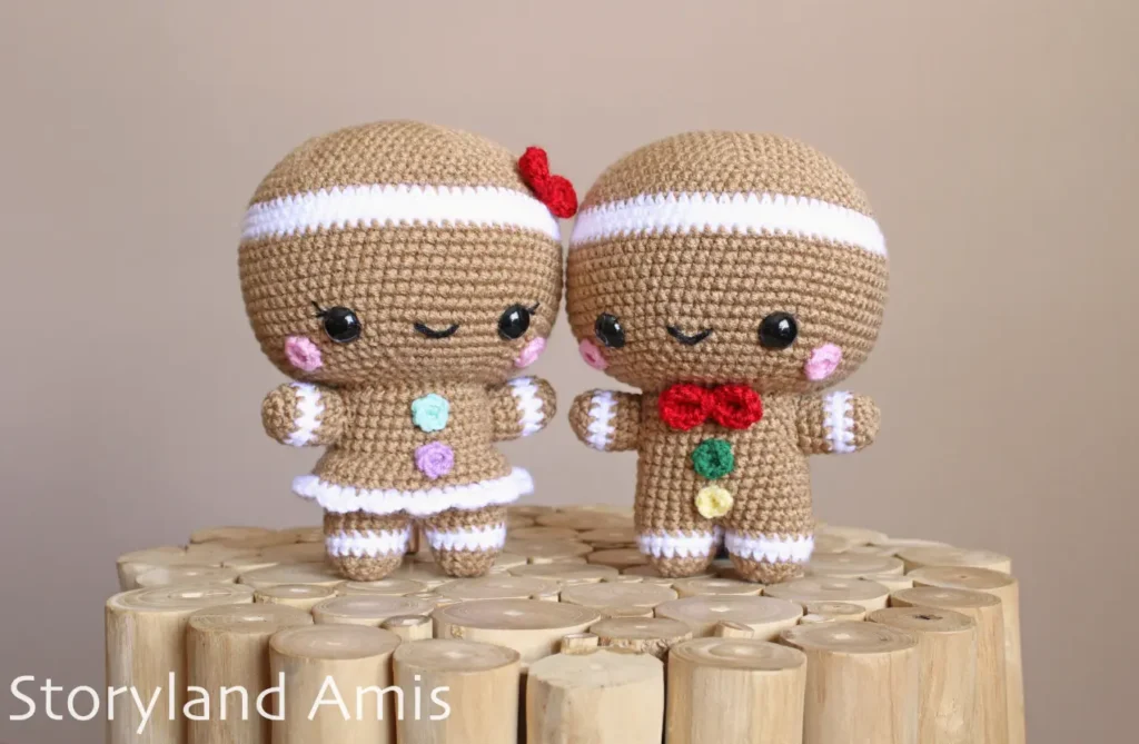 A crocheted gingerbread boy and girl stand on a wooden table.