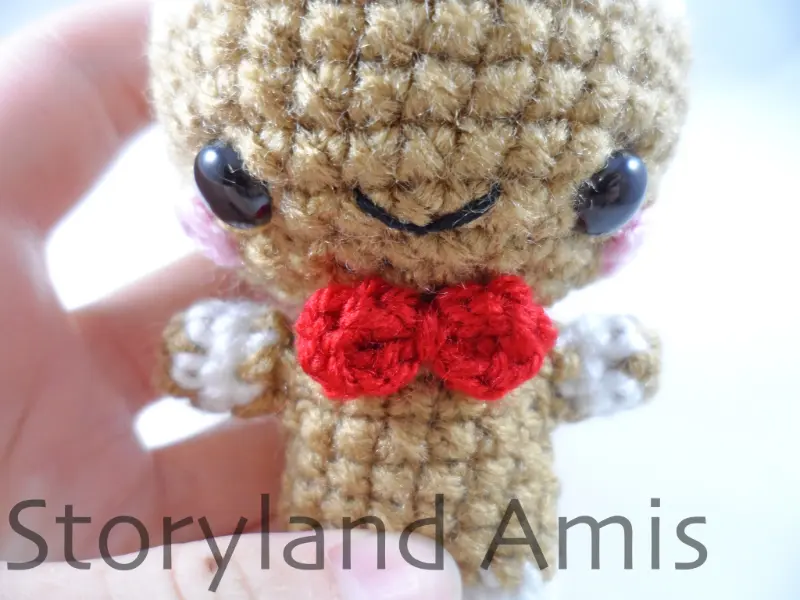 A close-up of the front of an amigurumi gingerbread boy.