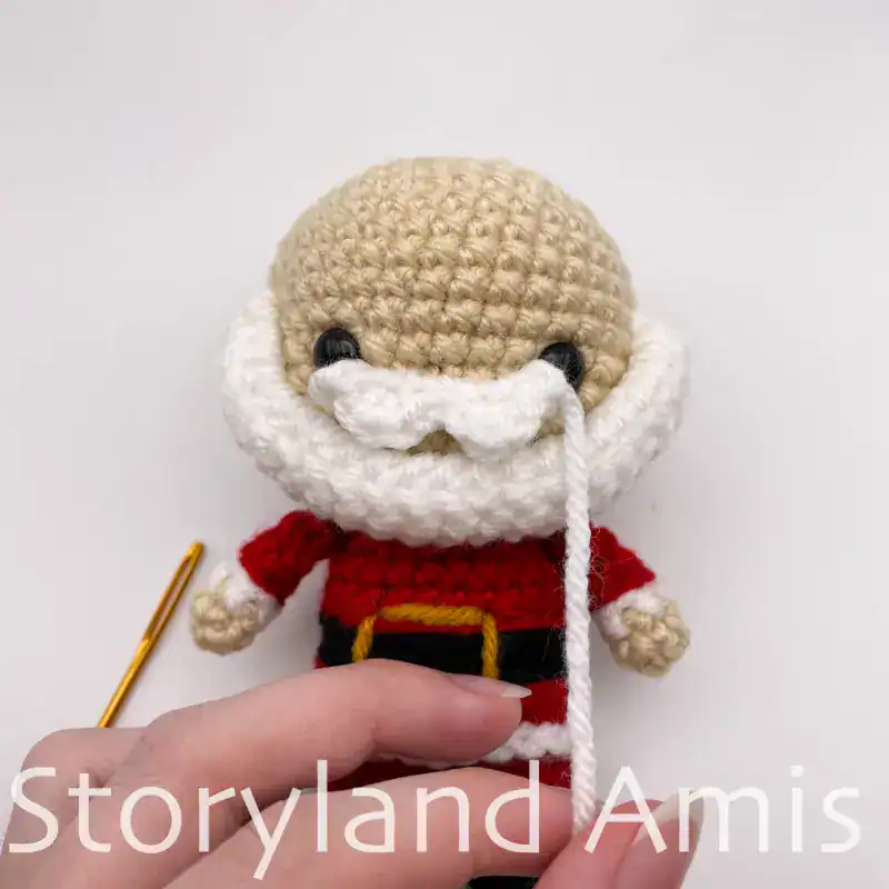 Close-up of the front of a partially completed amigurumi Santa Claus doll.