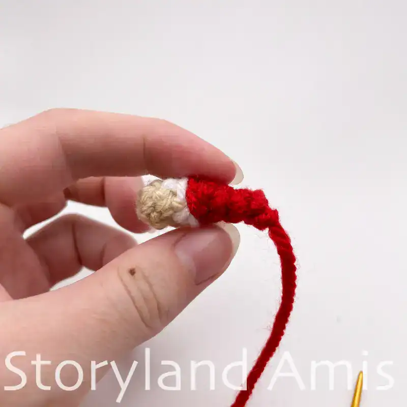 A hand holds a crocheted doll arm.