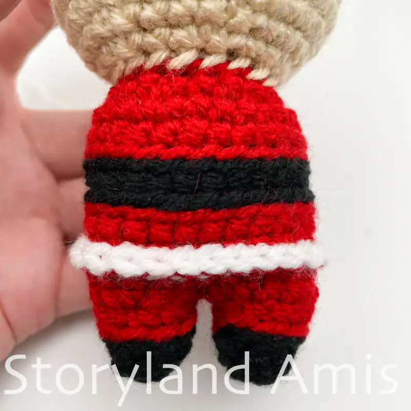 A close-up of the crocheted body of an amigurumi Santa Claus.
