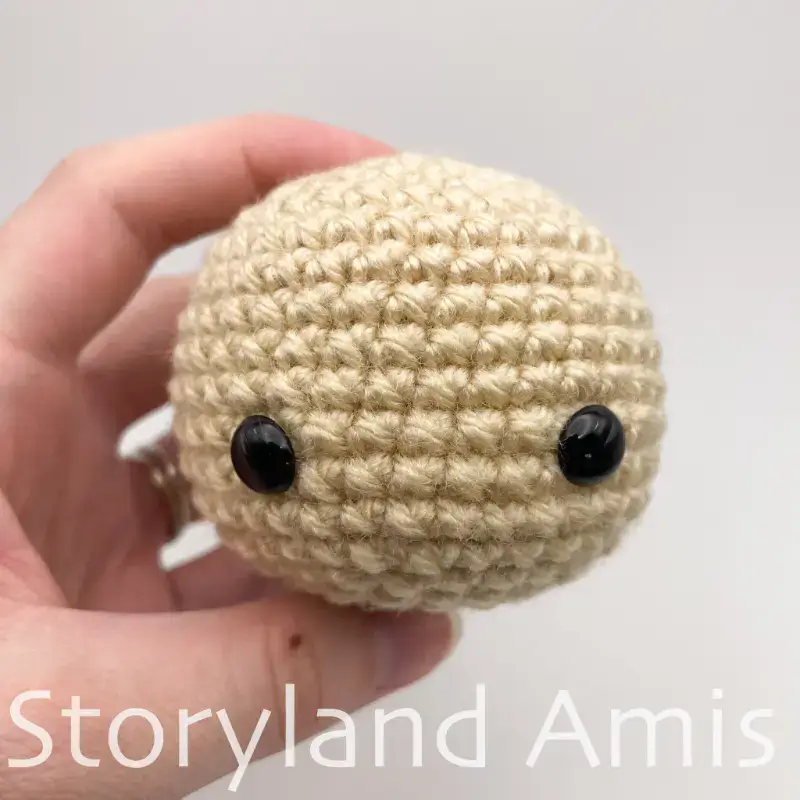 A crocheted head with black eyes and a smile.