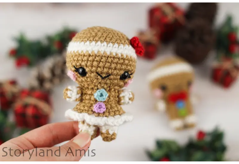 A hand holds up a mini crocheted gingerbread girl.