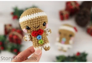 A hand holds up a mini gingerbread boy amigurumi.