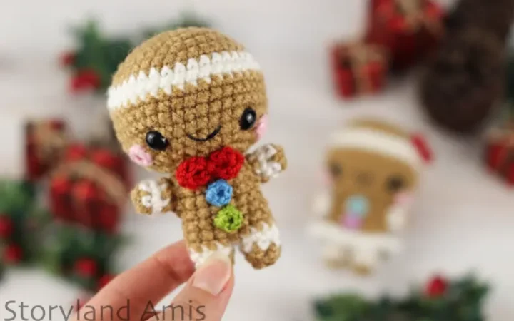 A hand holds up a mini gingerbread boy amigurumi.