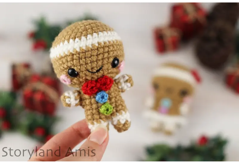 A hand holds up a mini gingerbread boy amigurumi.