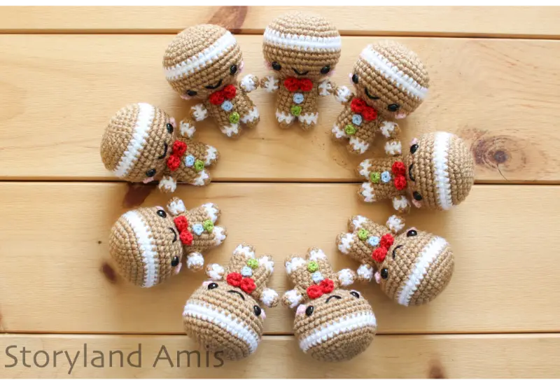 Nine crocheted gingerbread men lay in a circle on a wooden table.