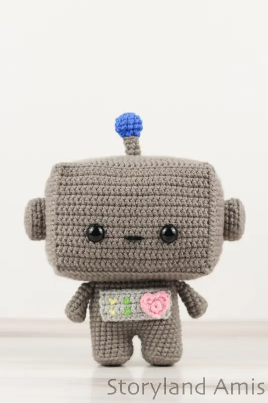 An amigurumi robot stands on a wooden table.