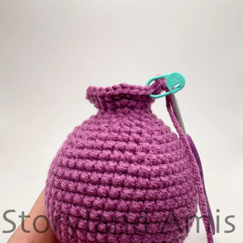 A close-up of the neck of an amigurumi stegosaurus dinosaur being crocheted.
