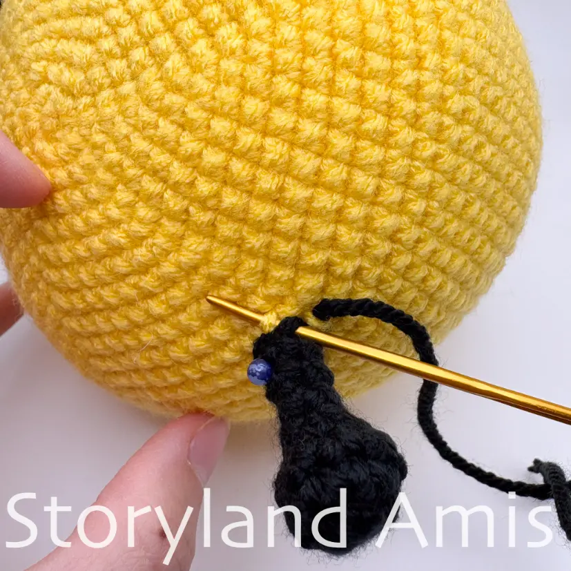 A close-up shows how to sew a crocheted antenna to an amigurumi bee's head using a tapestry needle.