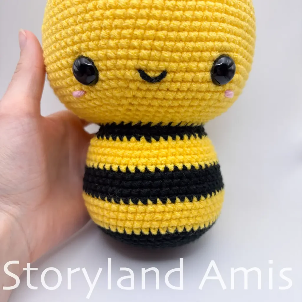 A close-up of the front of an amigurumi bee's body.