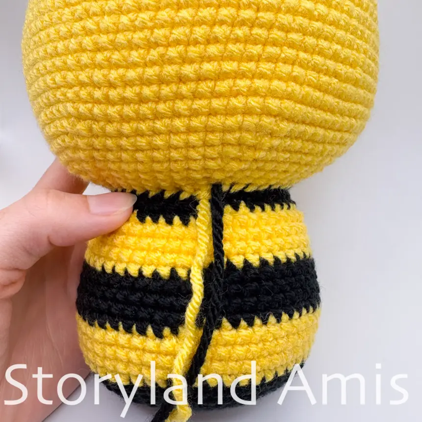 A close-up of the back of an amigurumi bee's body.