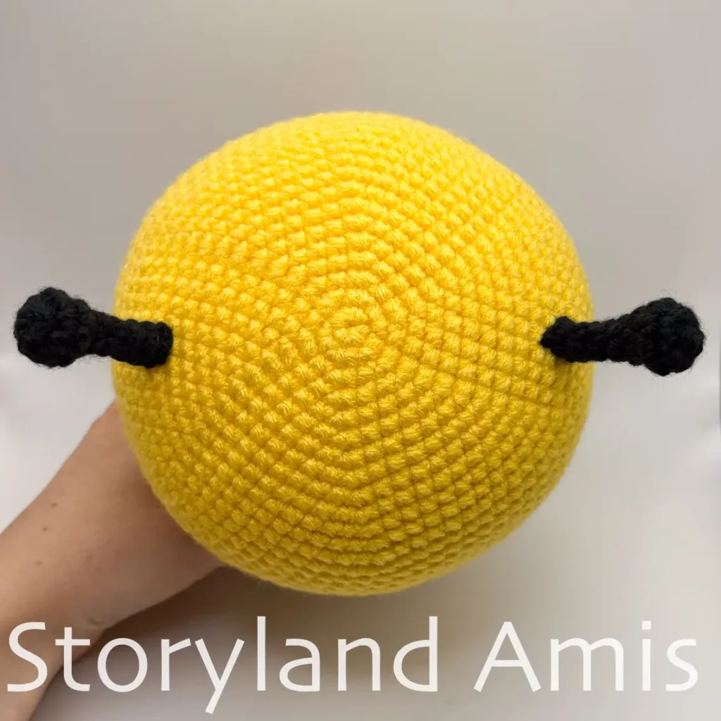 The top of an amigurumi bee head is shown from above.