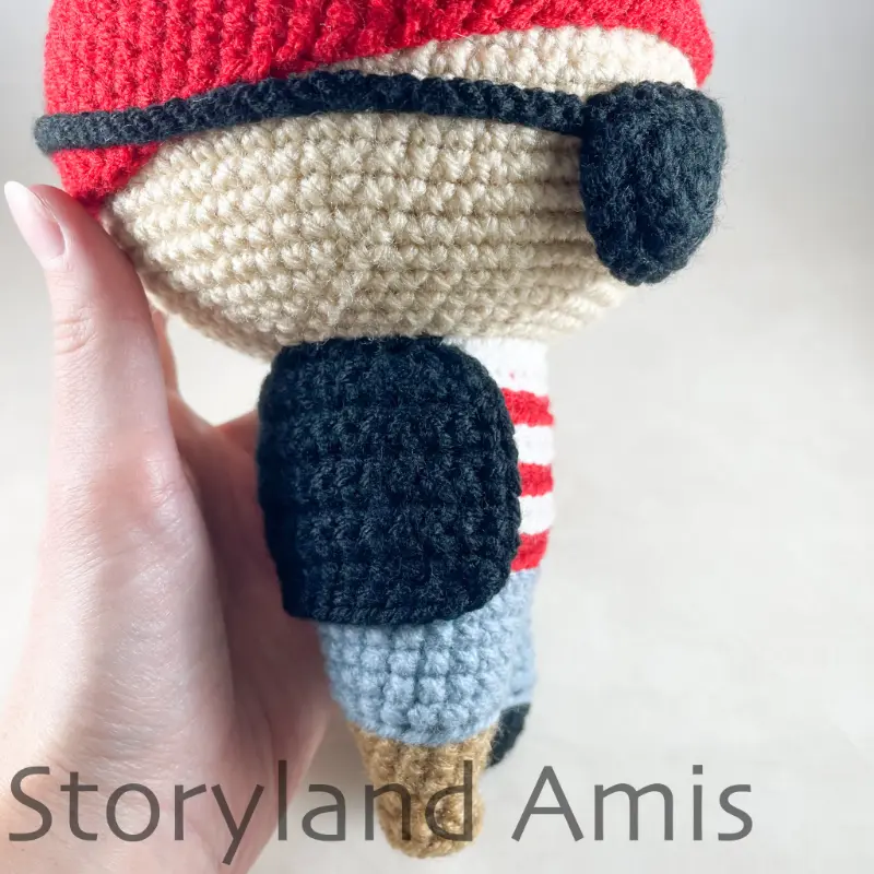 A close-up of an amigurumi pirate doll is shown from the side.