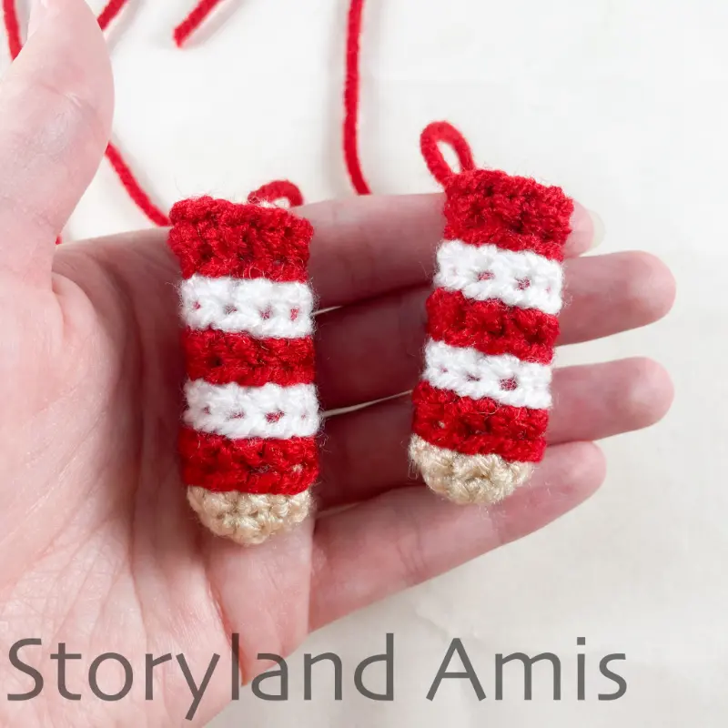 A hand holds two crocheted arms for an amigurumi doll.