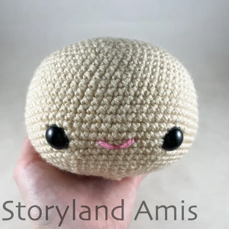 A hand holds an amigurumi pirate head.
