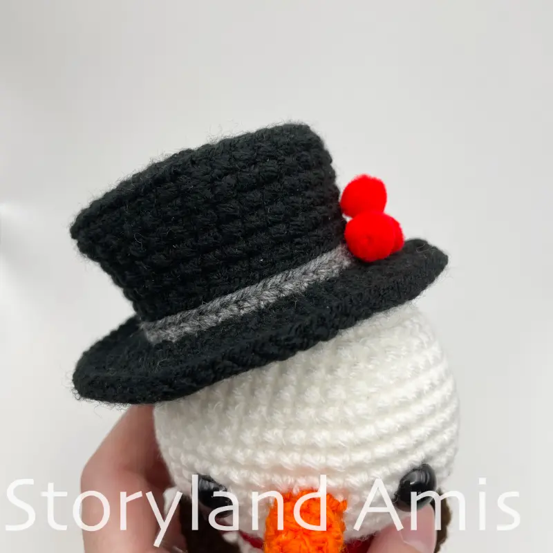 A close-up of a crocheted top hat on an amigurumi snowman's head, shown from the front.