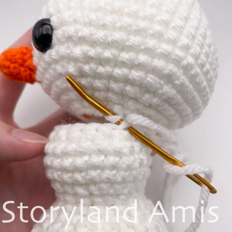 A close-up shows an amigurumi snowman's body and head being sewn together using a tapestry needle.