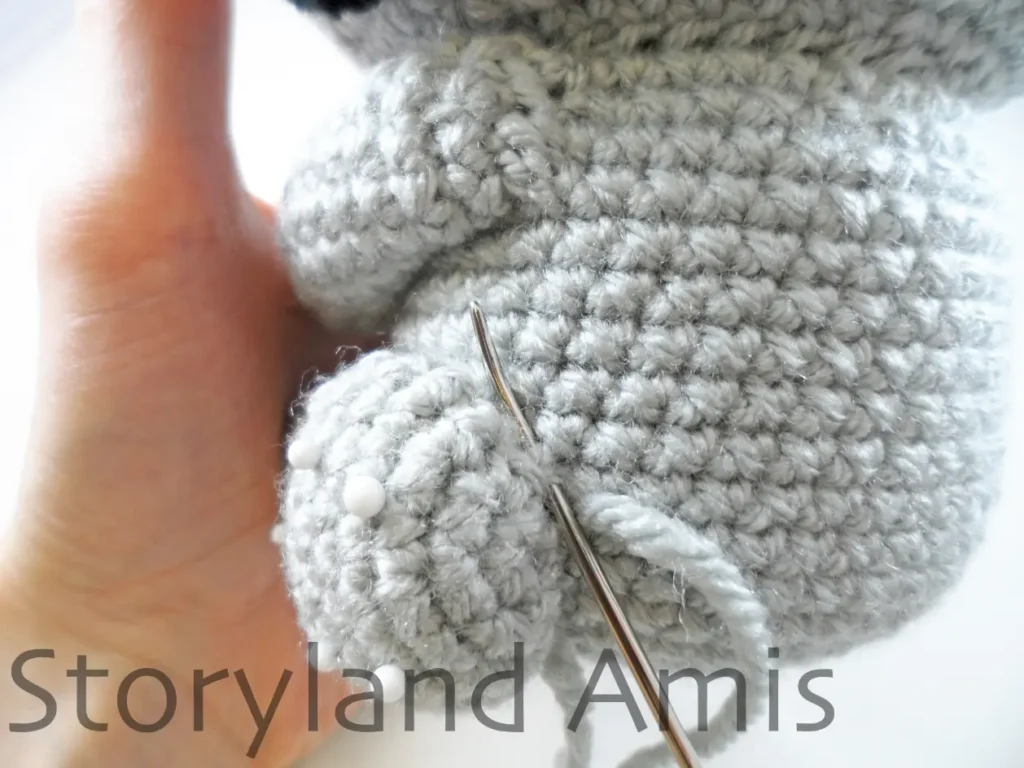 A close-up of the back of an amigurumi koala's leg as it is being sewn to its body.