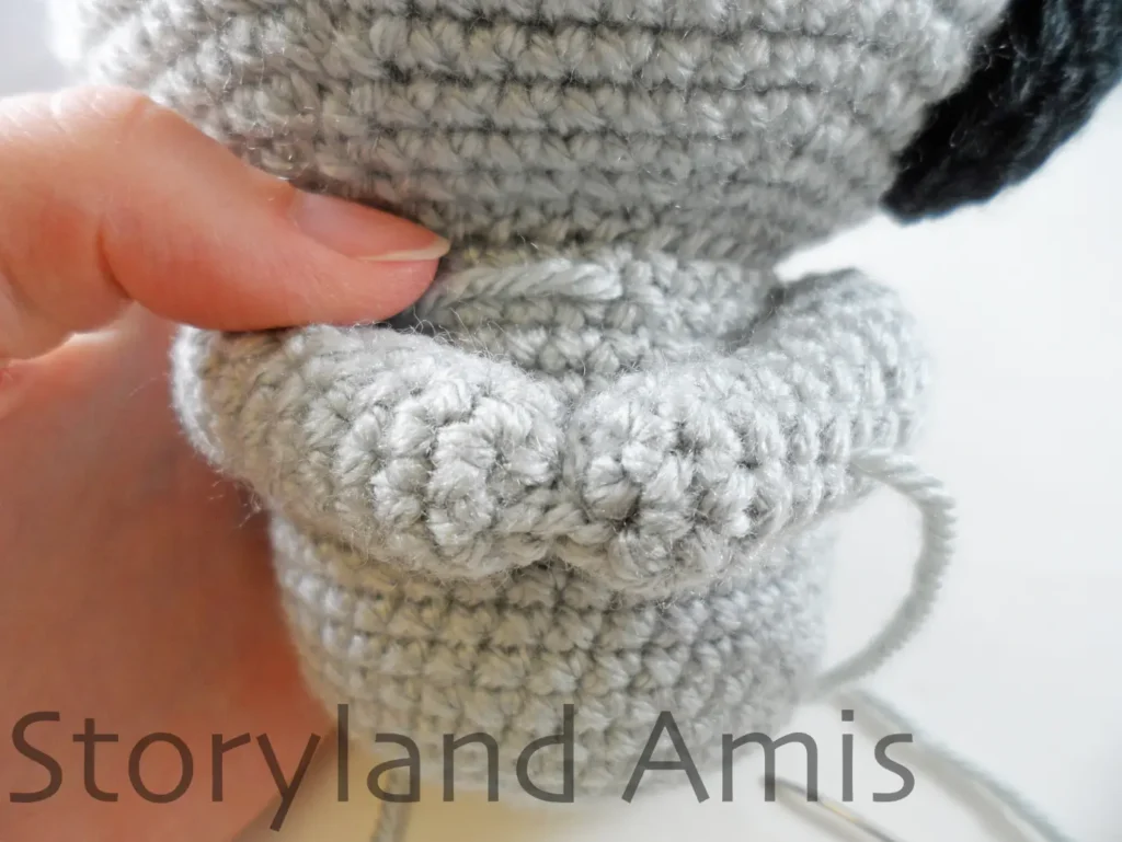 A close-up of two crocheted arms on an amigurumi koala.