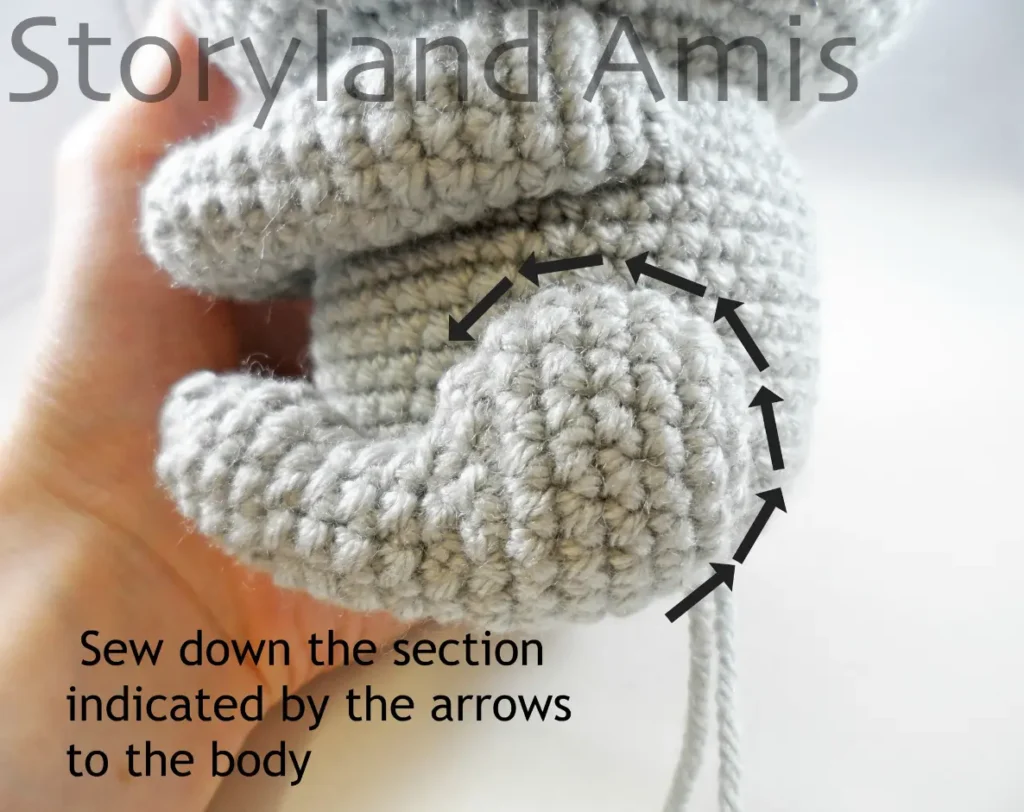 A close-up of an amigurumi koala leg with arrows and text indicating which part of the leg should be sewn to the body.